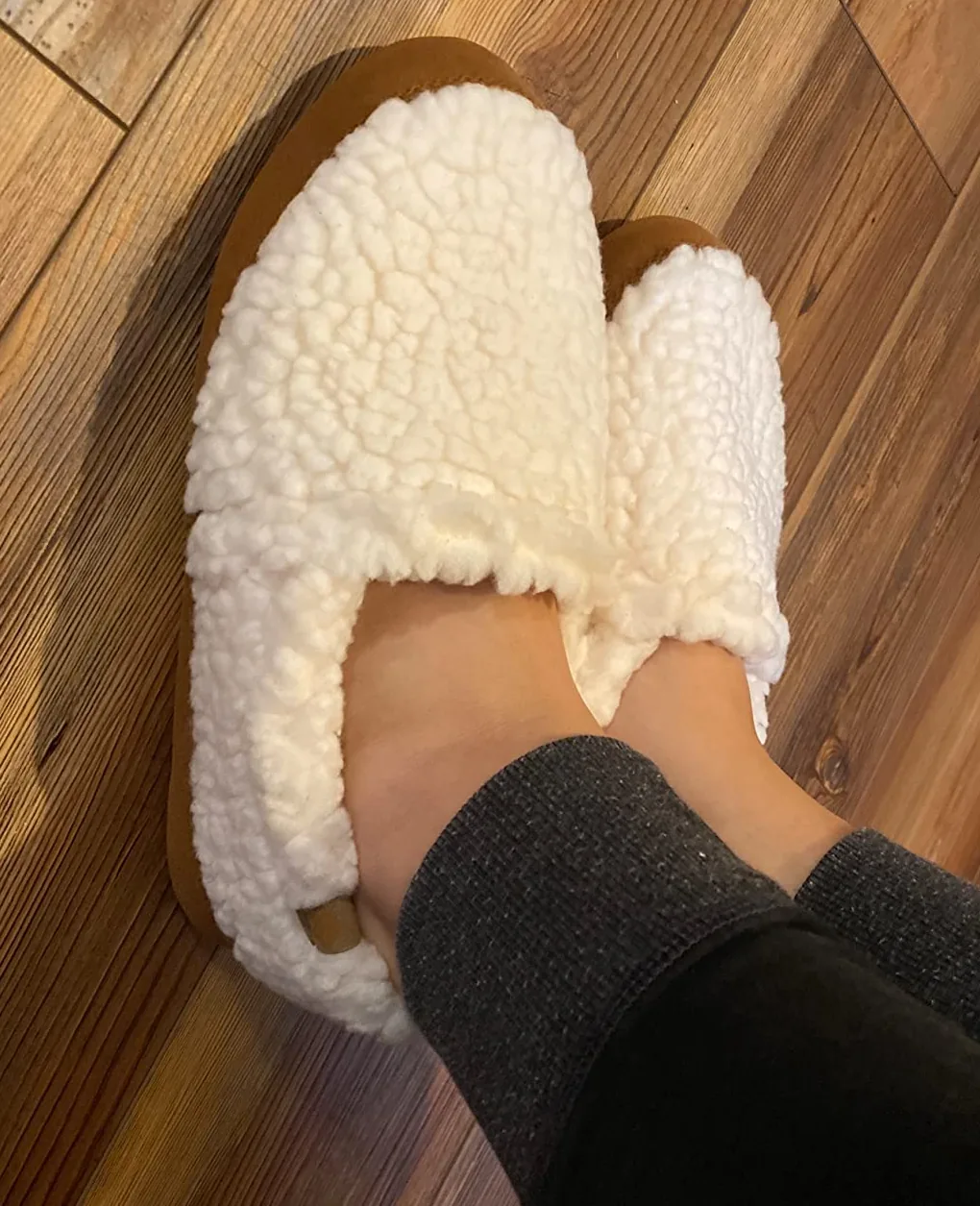 Close-up of white Acorn memory foam slippers being worn at home