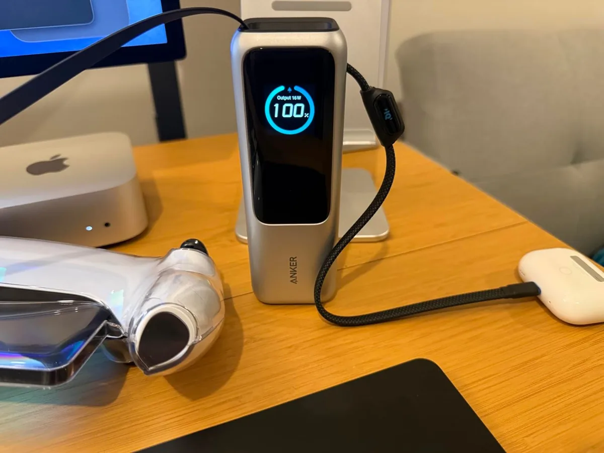 Anker power bank with a built-in USB-C cable charging earbuds on a desk