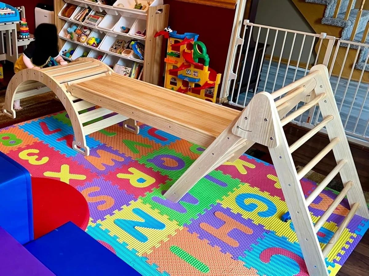 Wooden climbing triangle, ramp and arch climber set up on a colorful foam play mat