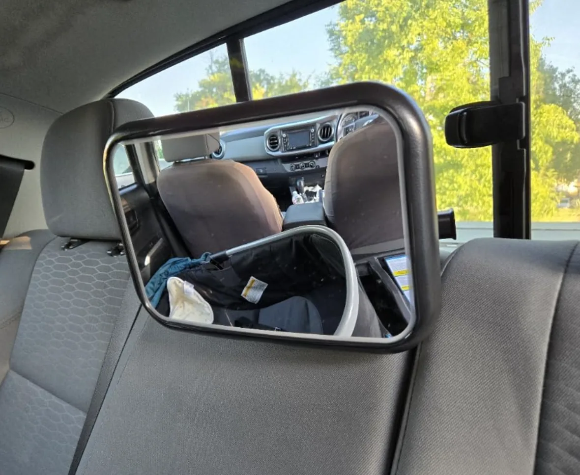 Baby car mirror on a rear headrest reflecting the car seat and front dashboard