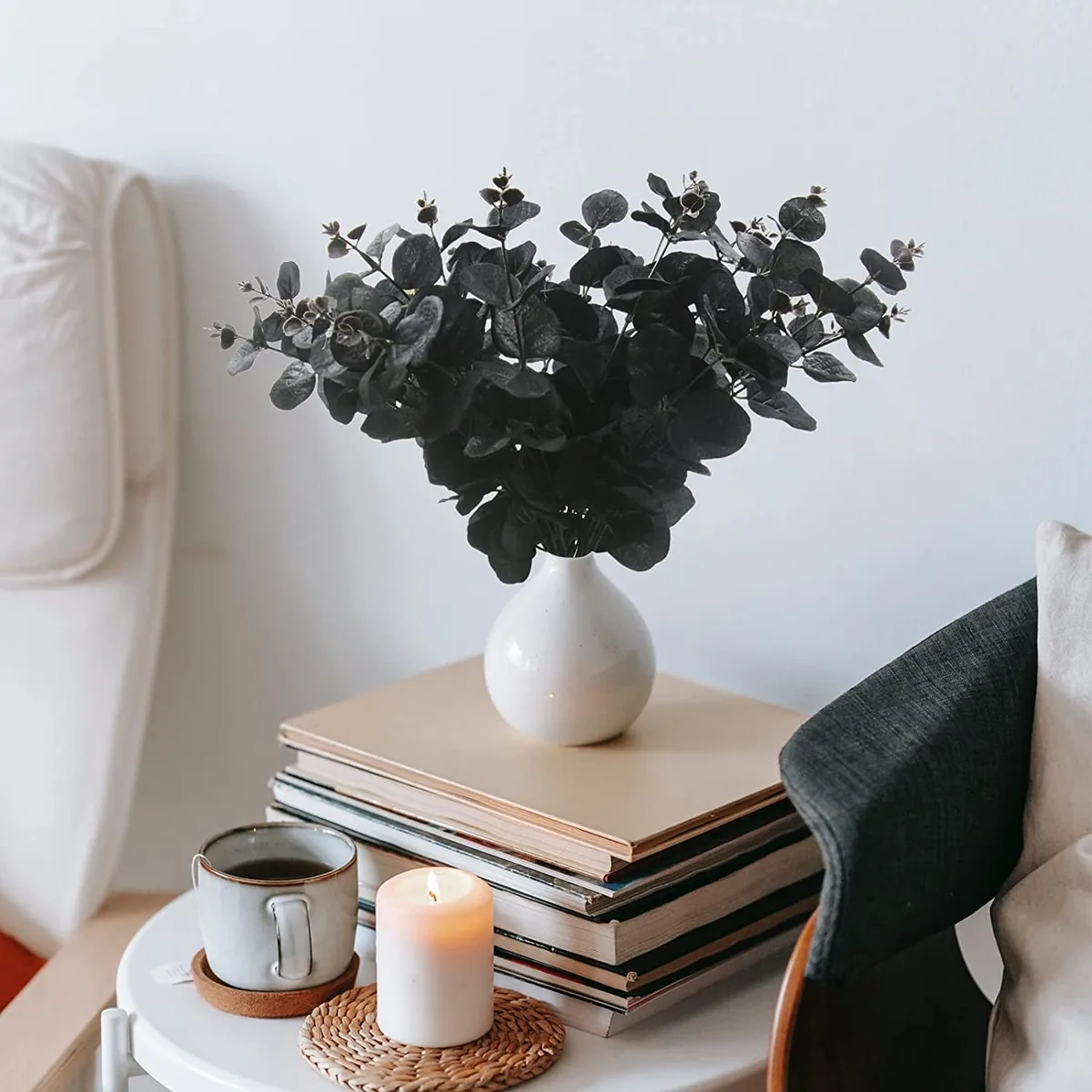 Black faux eucalyptus stems in a vase on a stack of books