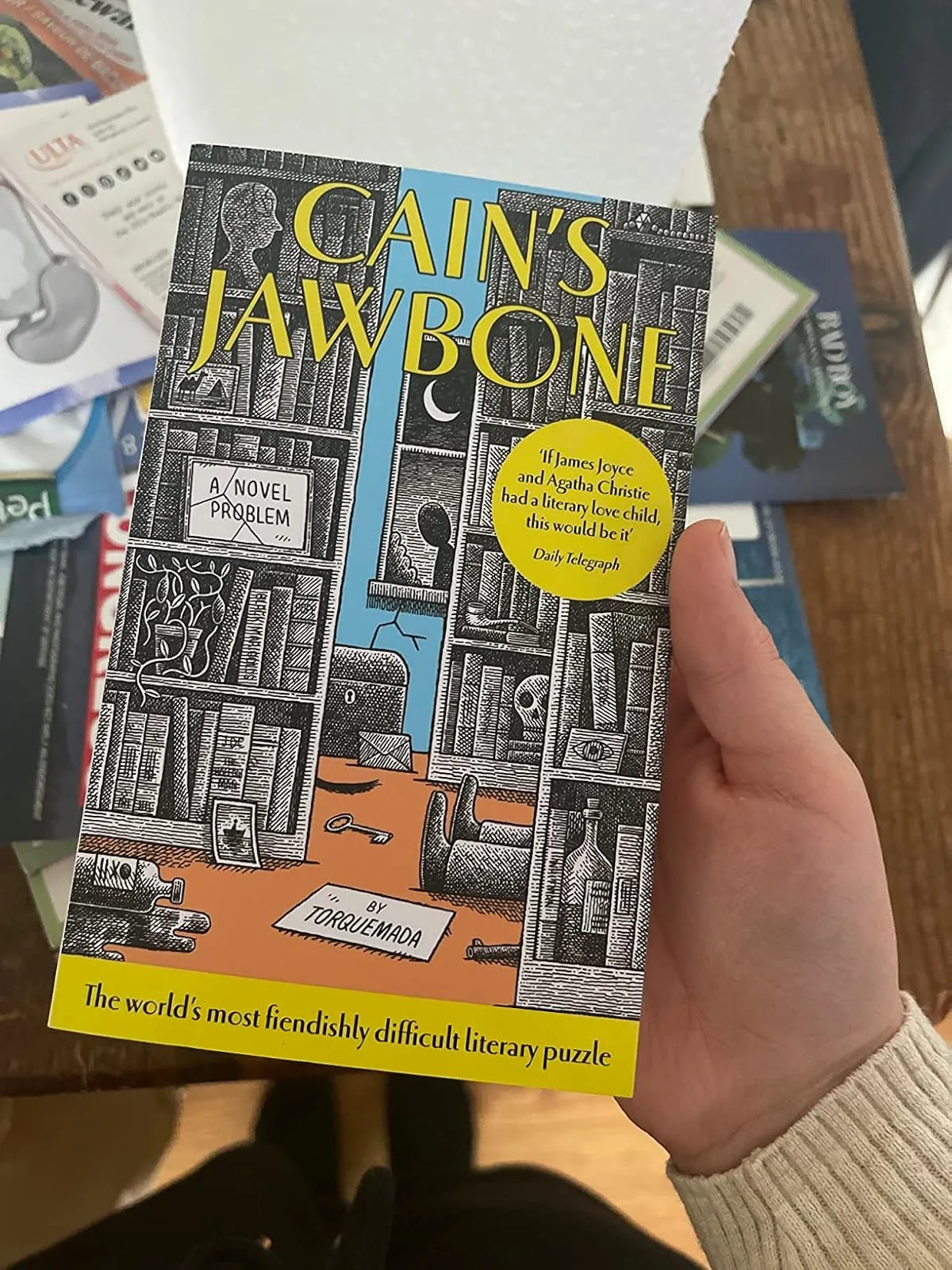 Hand holding the Cain's Jawbone literary murder mystery puzzle