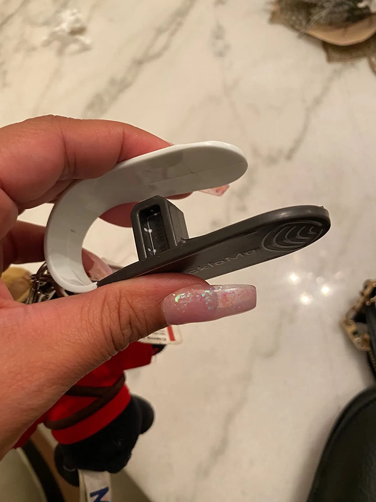 Hand holding a small car seat buckle release tool