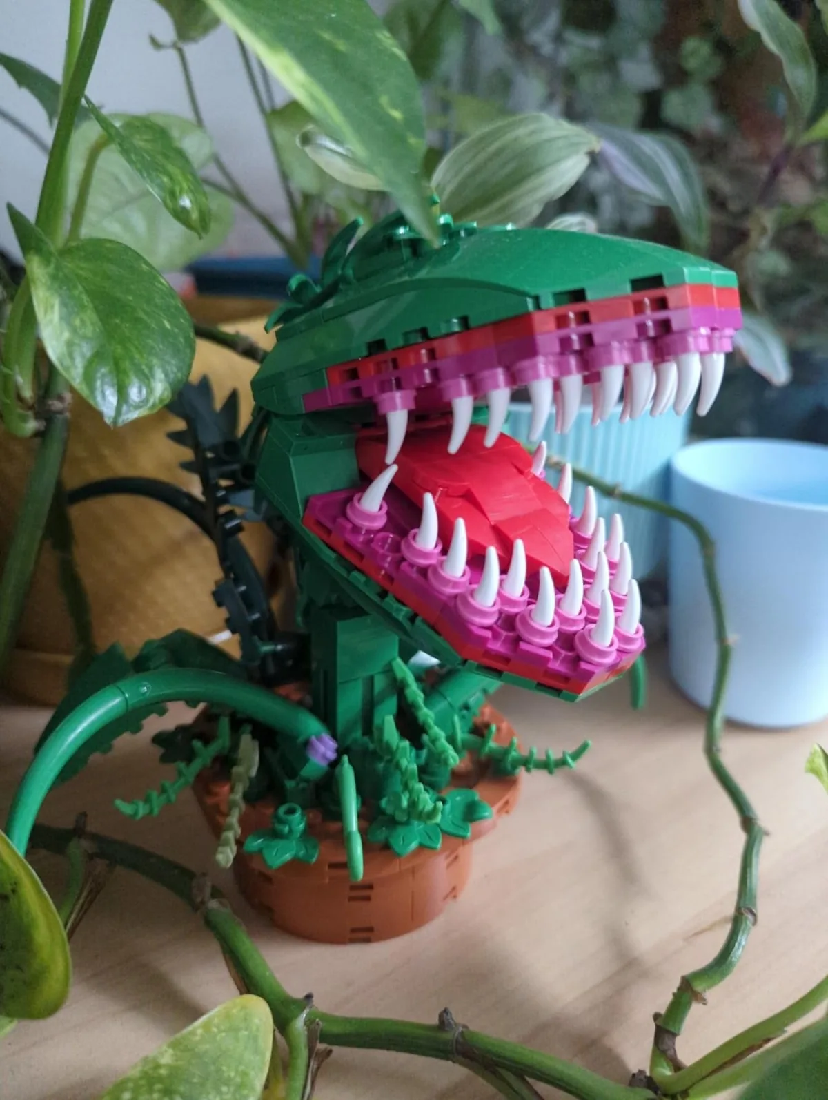 Brick-built carnivorous plant with open jaws displayed among real leaves