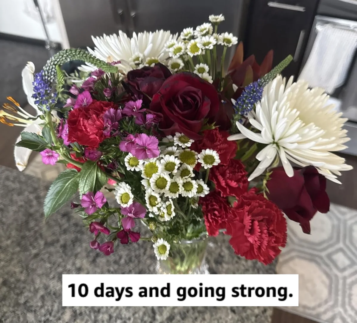 Bright bouquet of roses and daisies in a clear vase of clean water