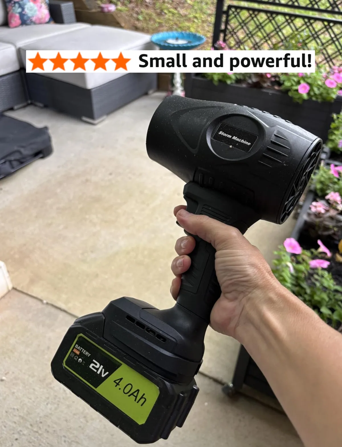 Hand holding a cordless handheld leaf blower on a patio