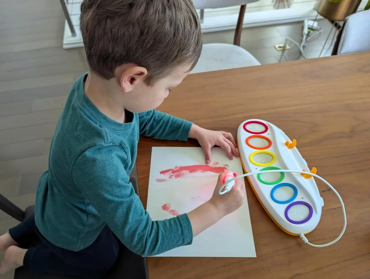Child painting at a table with the Crayola Color Wonder light-up brush and paint station