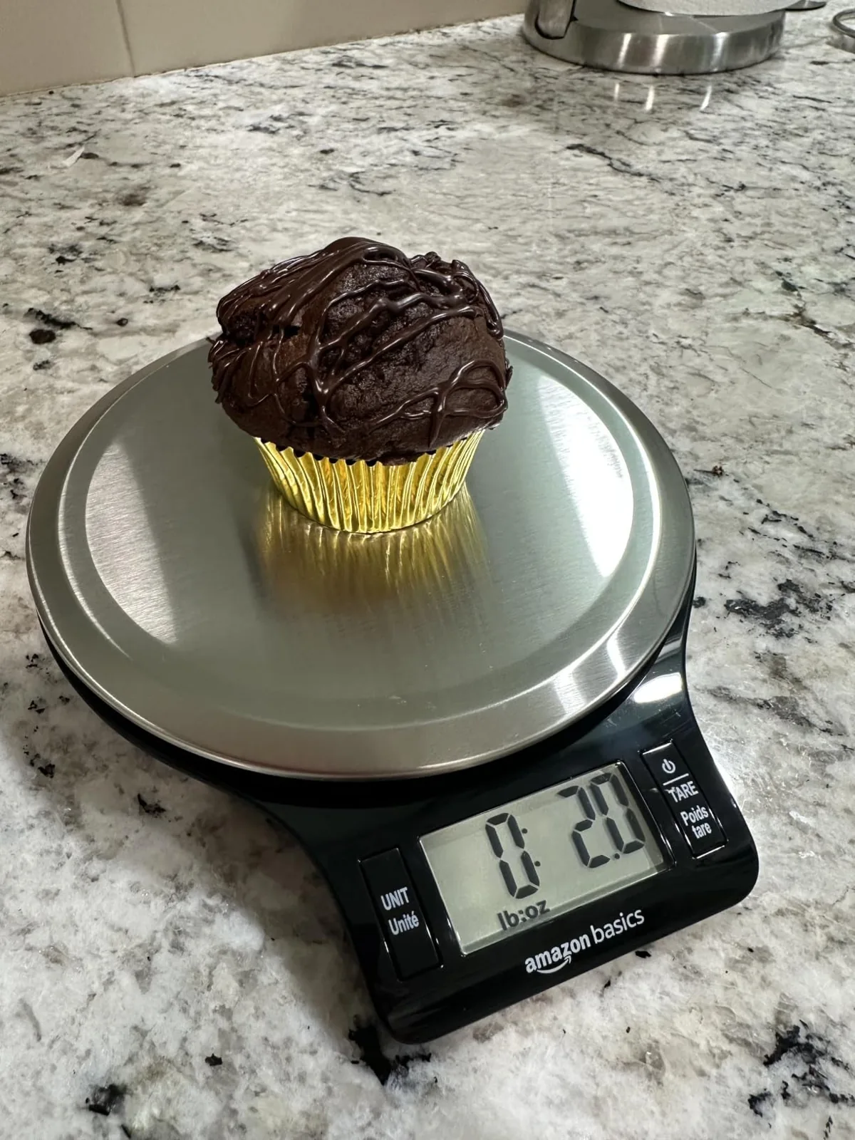 Chocolate frosted cupcake sitting on a black digital kitchen scale