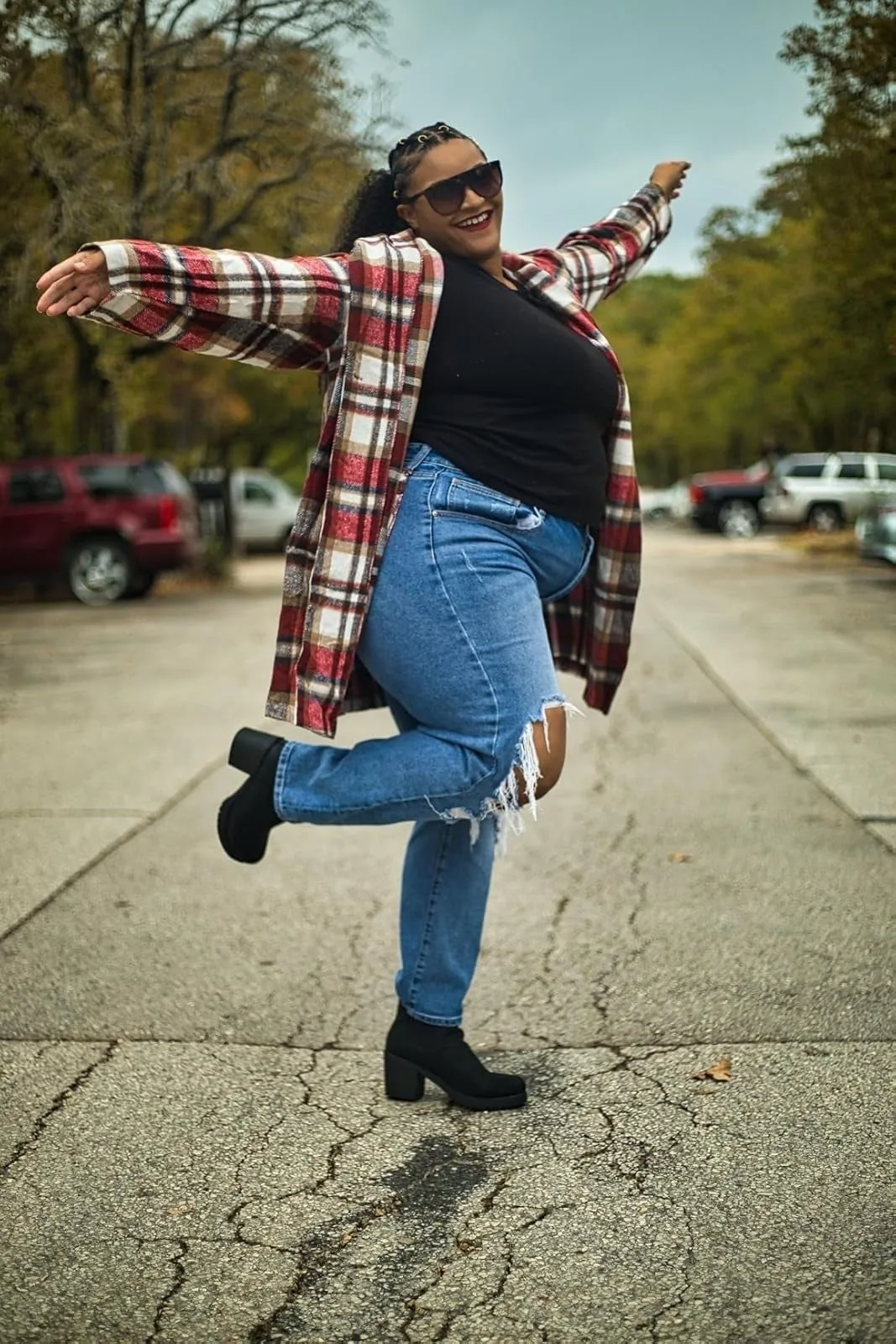 Person in a plaid coat and ripped jeans wearing heeled suede Chelsea boots outdoors