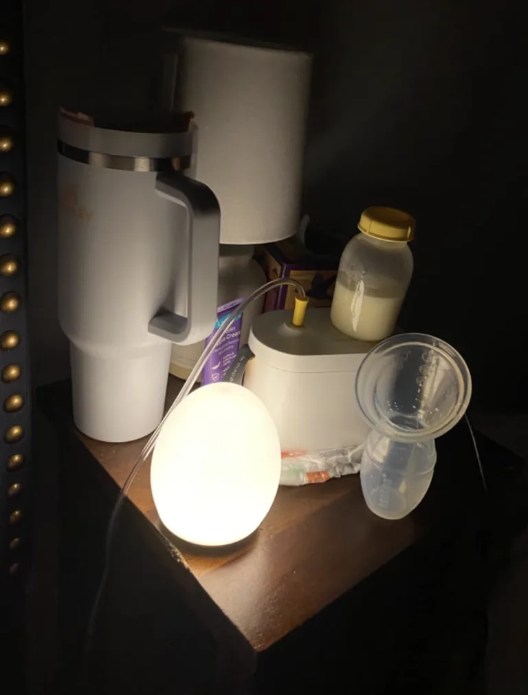 Egg-shaped night-light glowing softly on a bedside table with a bottle and pump parts