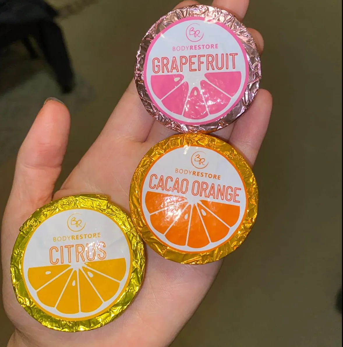 Hand holding foil-wrapped essential oil shower steamers
