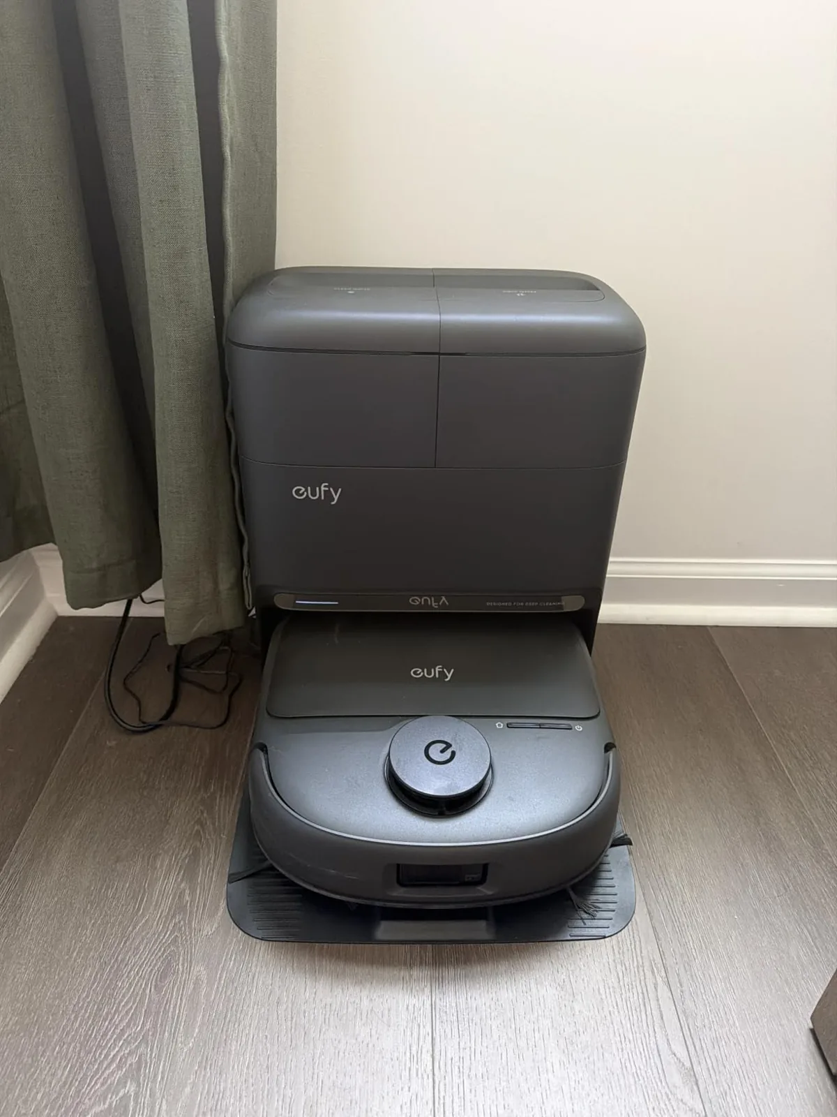 Eufy robot vacuum and mop parked in its self-emptying station on a wood floor