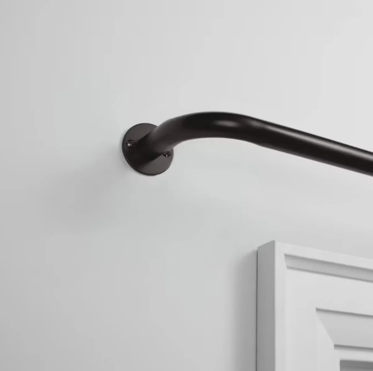 Curved end of a French return curtain rod mounted to a wall