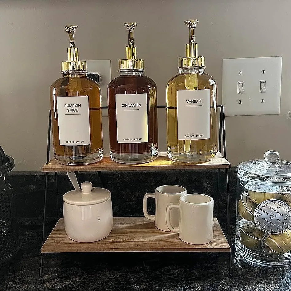 Glass coffee syrup dispenser bottles lined up on a home coffee bar shelf