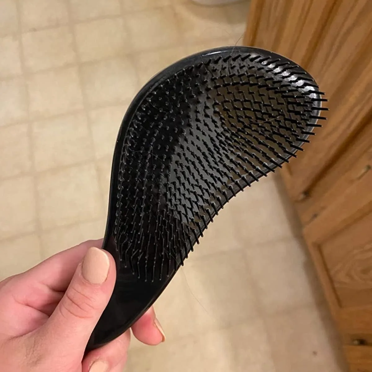 Hand holding a black Crave Naturals Glide Thru detangling brush