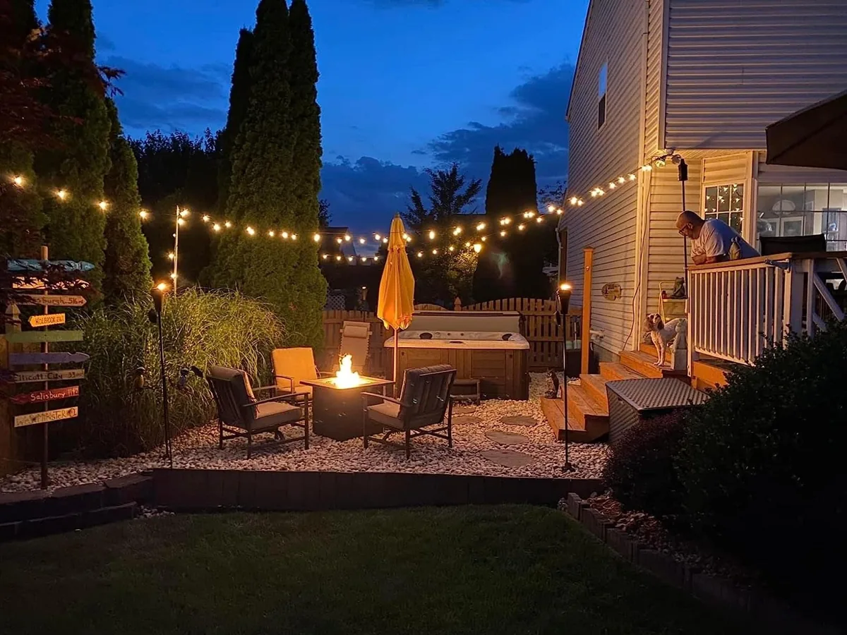 Globe string lights glowing above a backyard seating area at dusk