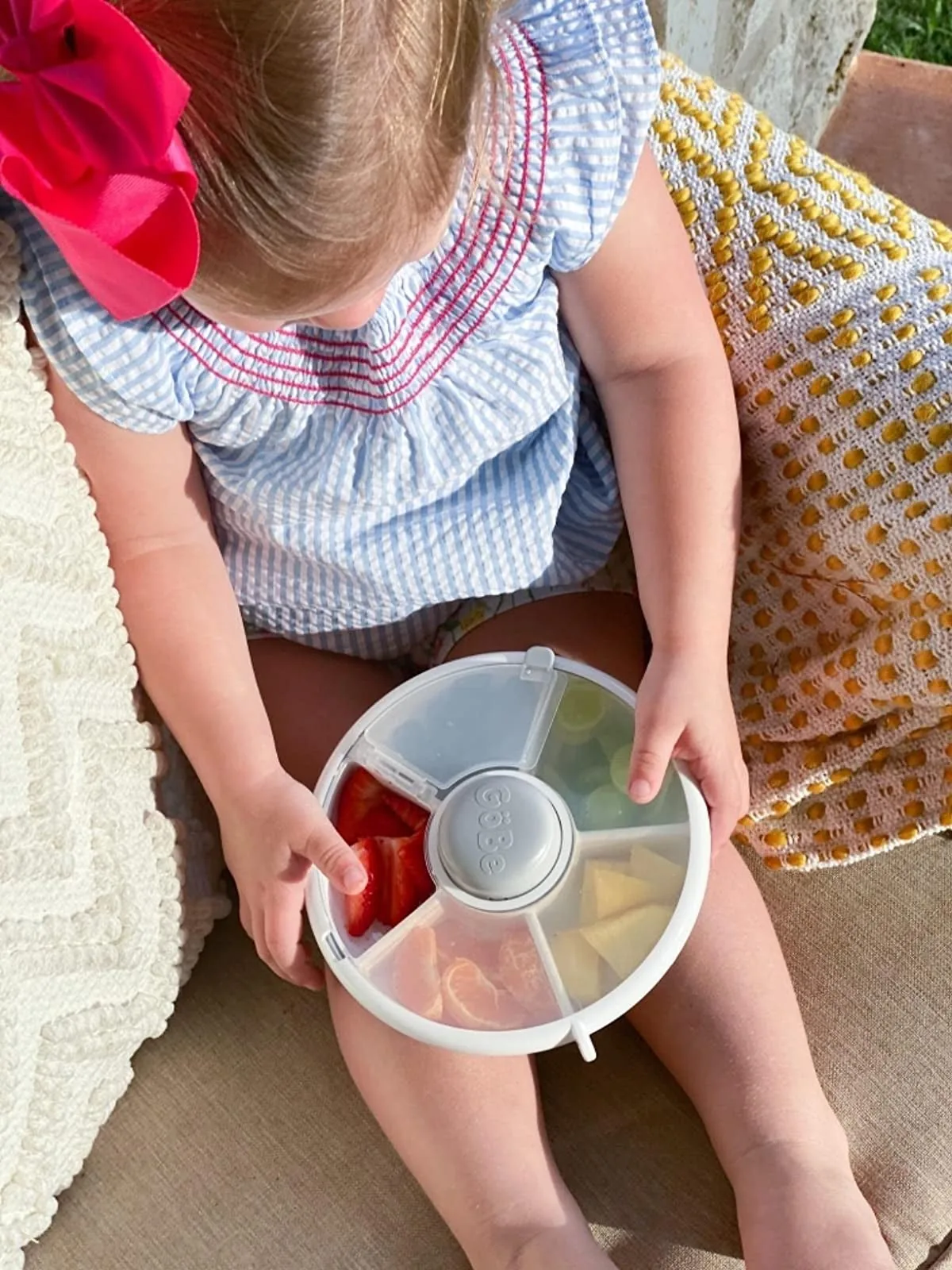 Child holding a round spinning snack container with several compartments