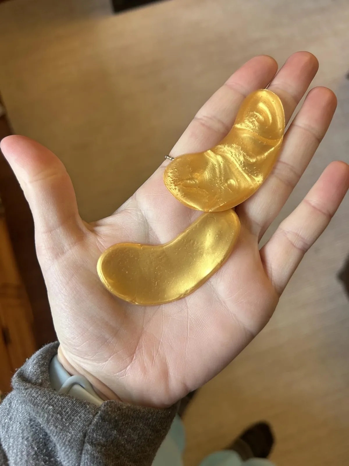 Hand holding two gold gel under-eye patches