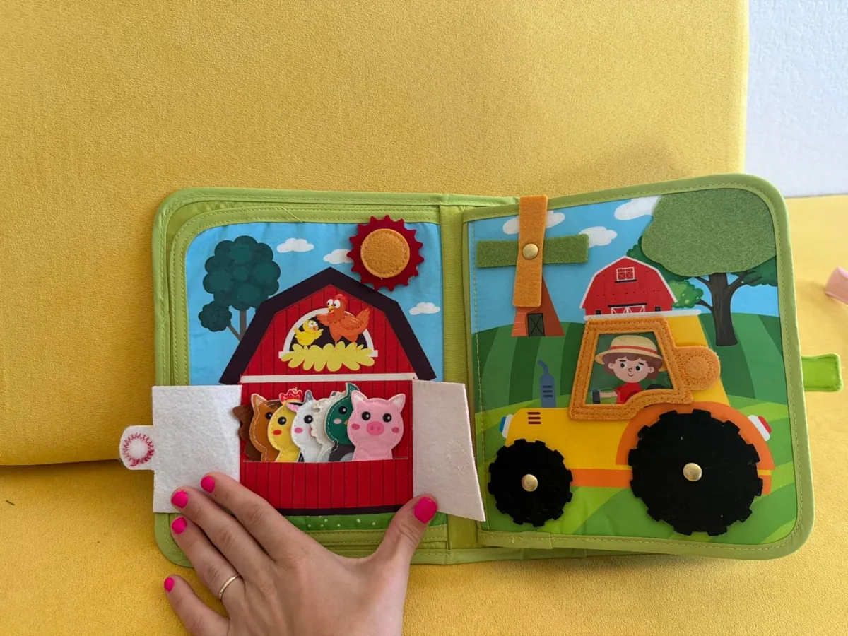 Open toddler busy book with felt farm animals, barn door and tractor