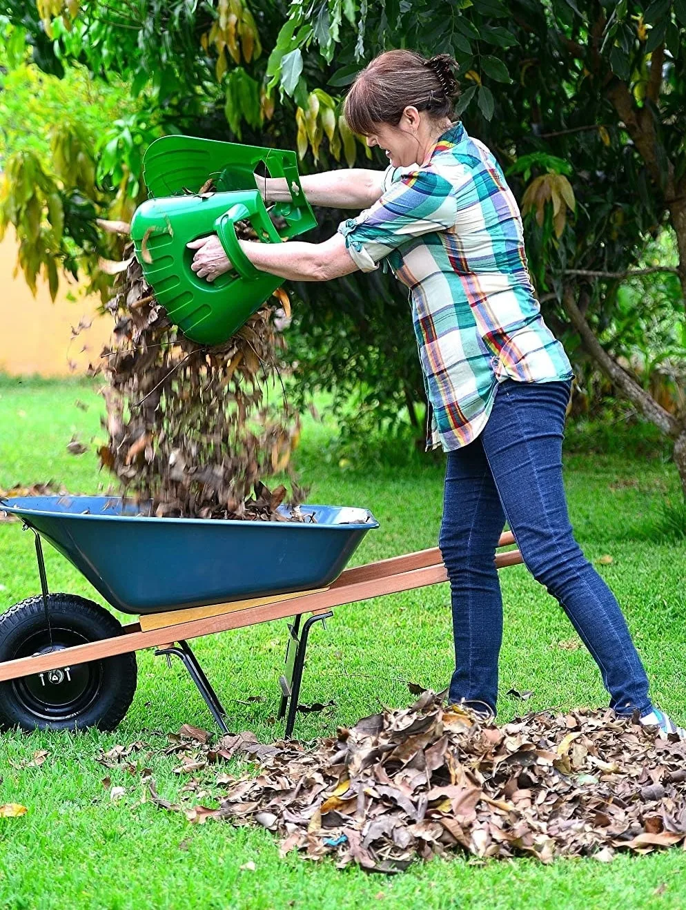Person using oversized handheld leaf scoops to lift a pile of leaves