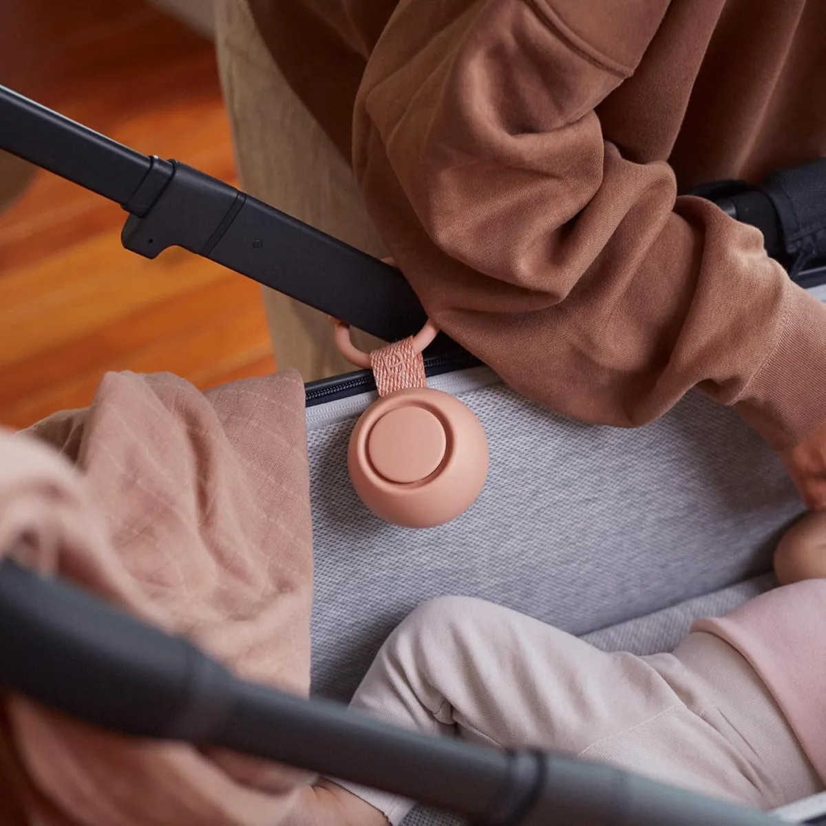 Peach Hatch Rest Go portable sound machine clipped inside a stroller next to a sleeping baby
