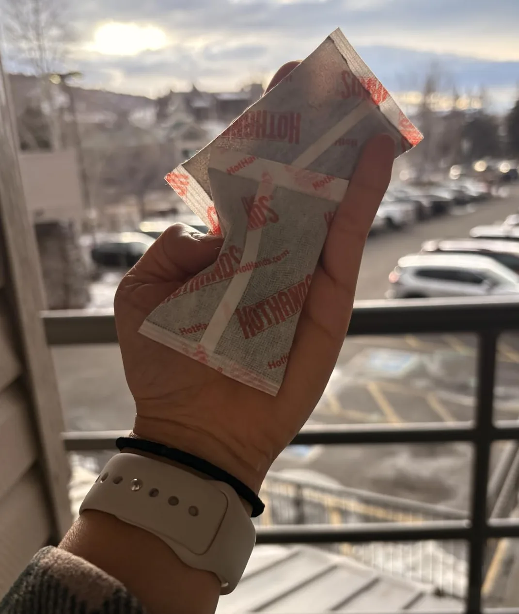 Hand holding two HotHands hand warmer packets outdoors