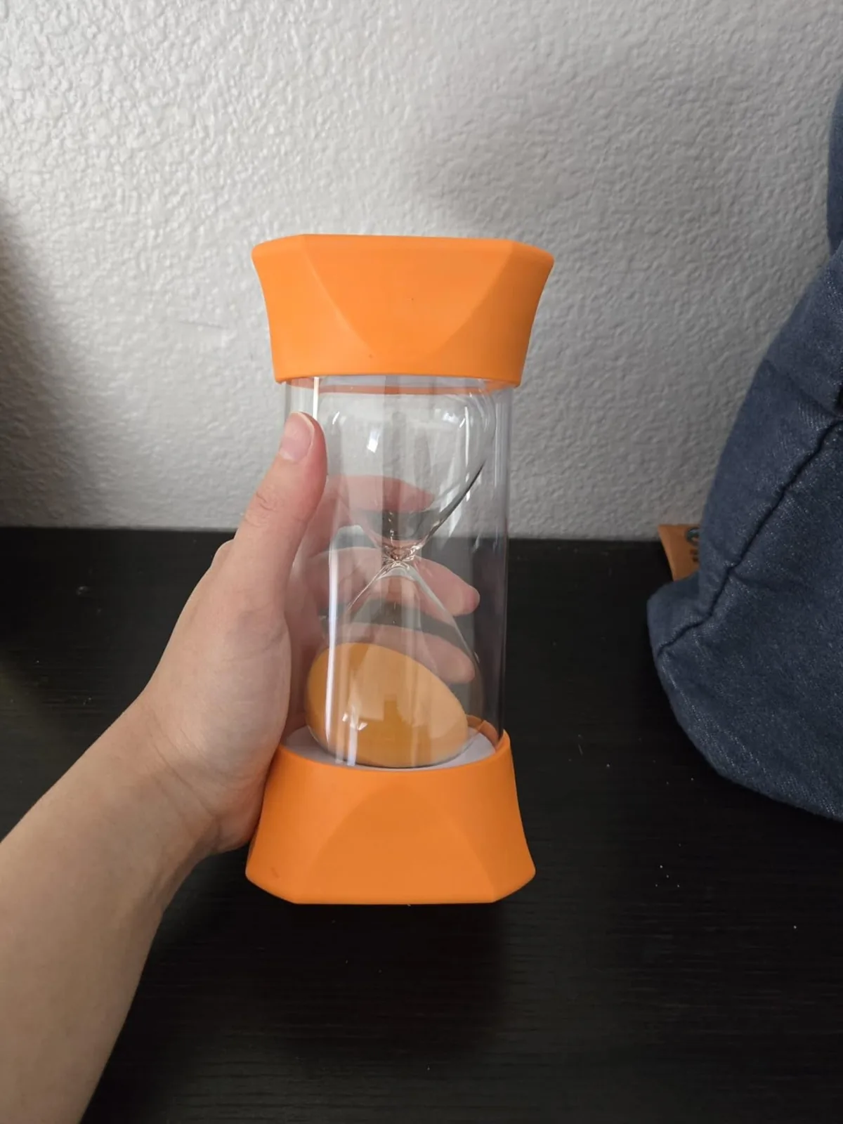Jumbo sand timer with orange rubber end caps held in a hand