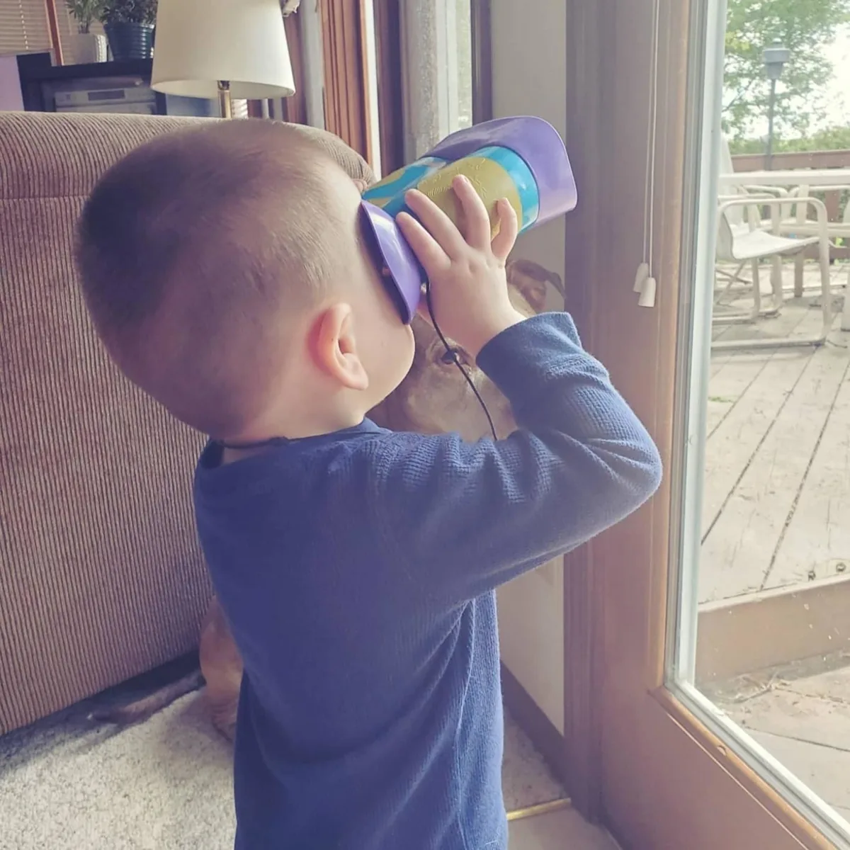 Child looking through chunky kid binoculars at a window