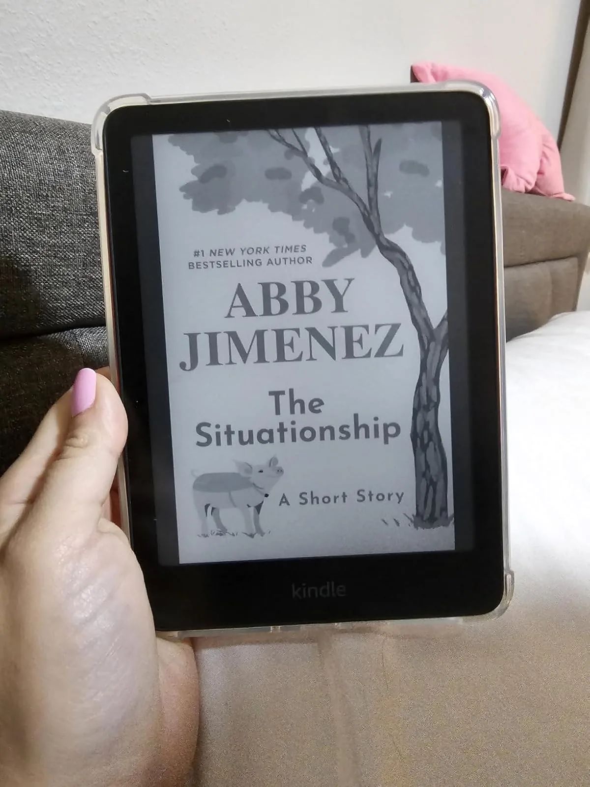 Hand holding a Kindle Paperwhite showing a book cover
