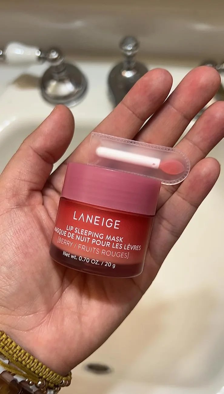 Hand holding a jar of Laneige Lip Sleeping Mask in Berry with its applicator