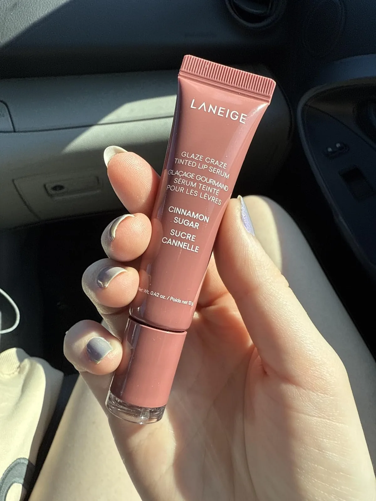 Hand holding a Laneige Glaze Craze tinted lip serum tube in Cinnamon Sugar