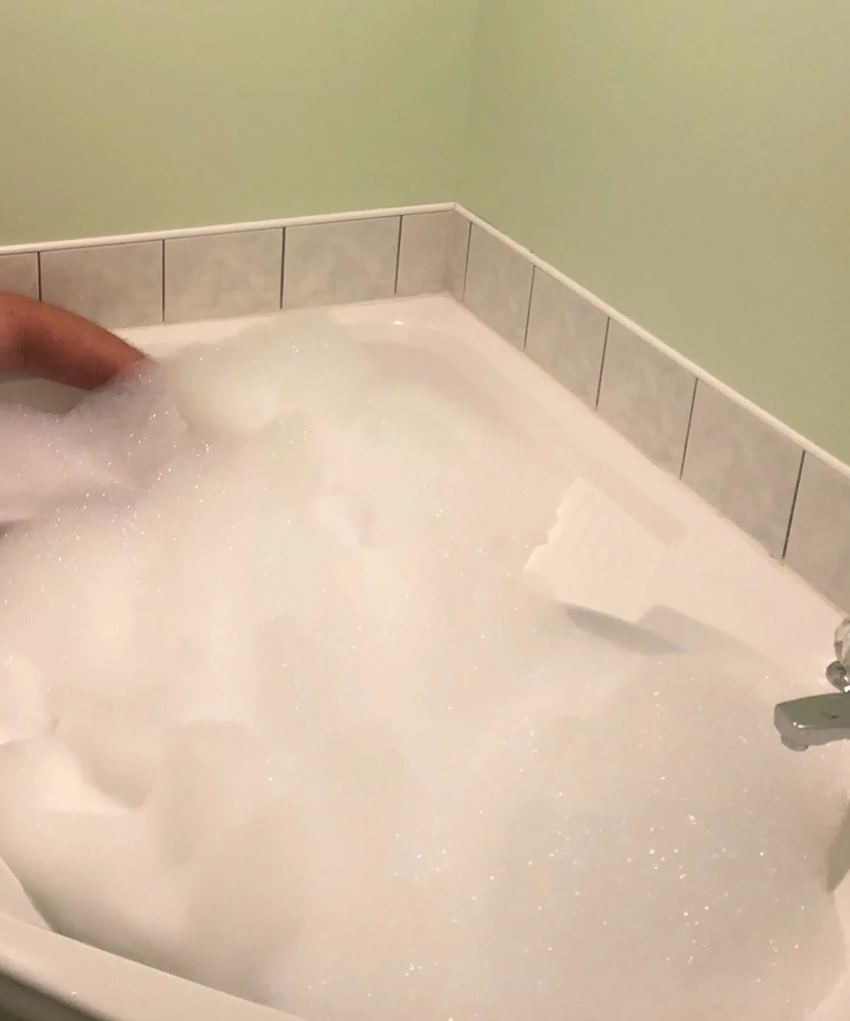 Tall white bubbles filling a bathtub