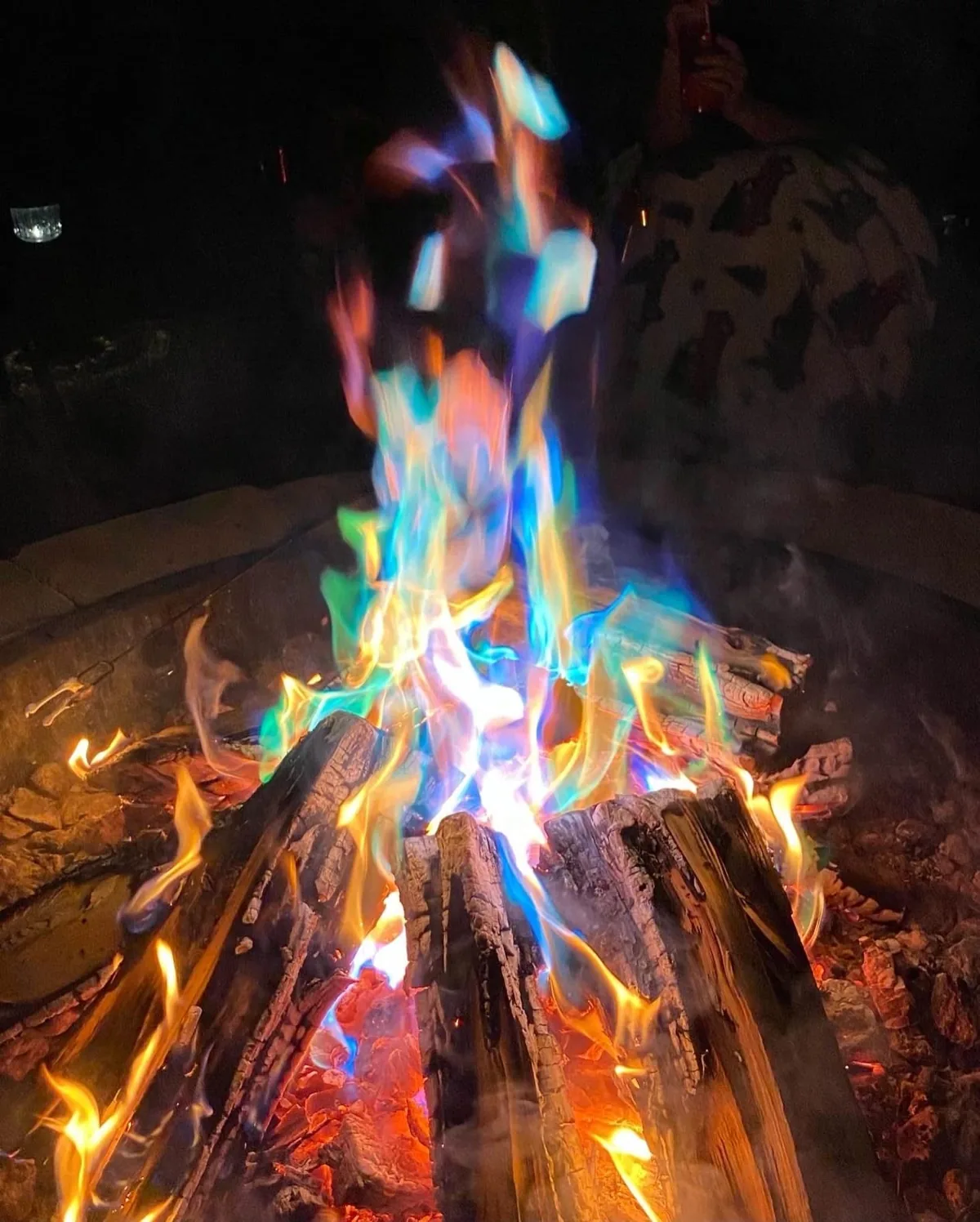 Campfire burning with blue, green and purple flames at night