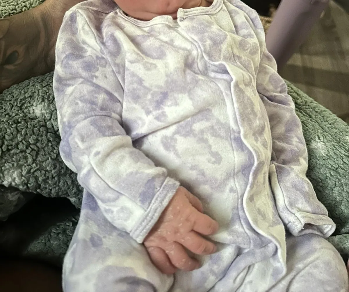 Baby wearing lavender organic cotton footie pajamas with a magnetic closure
