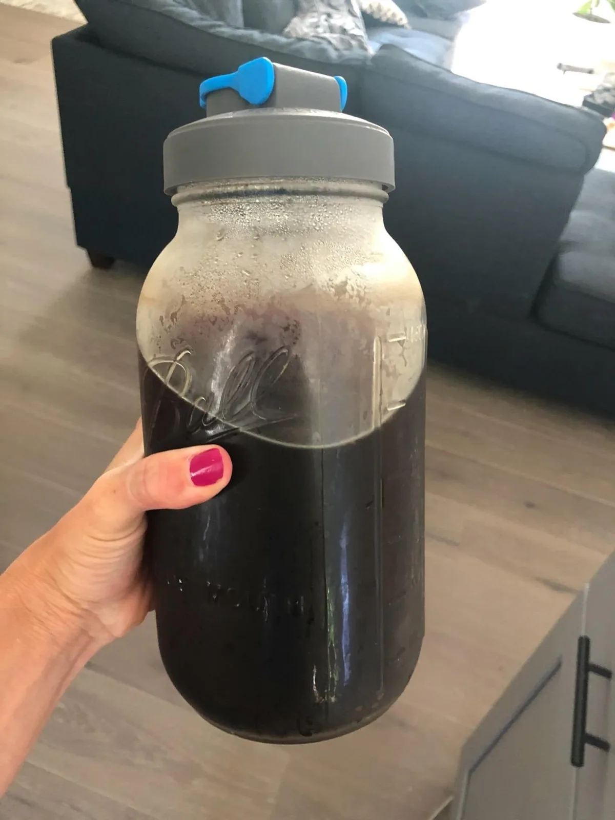Hand holding a mason jar cold brew coffee maker filled with coffee