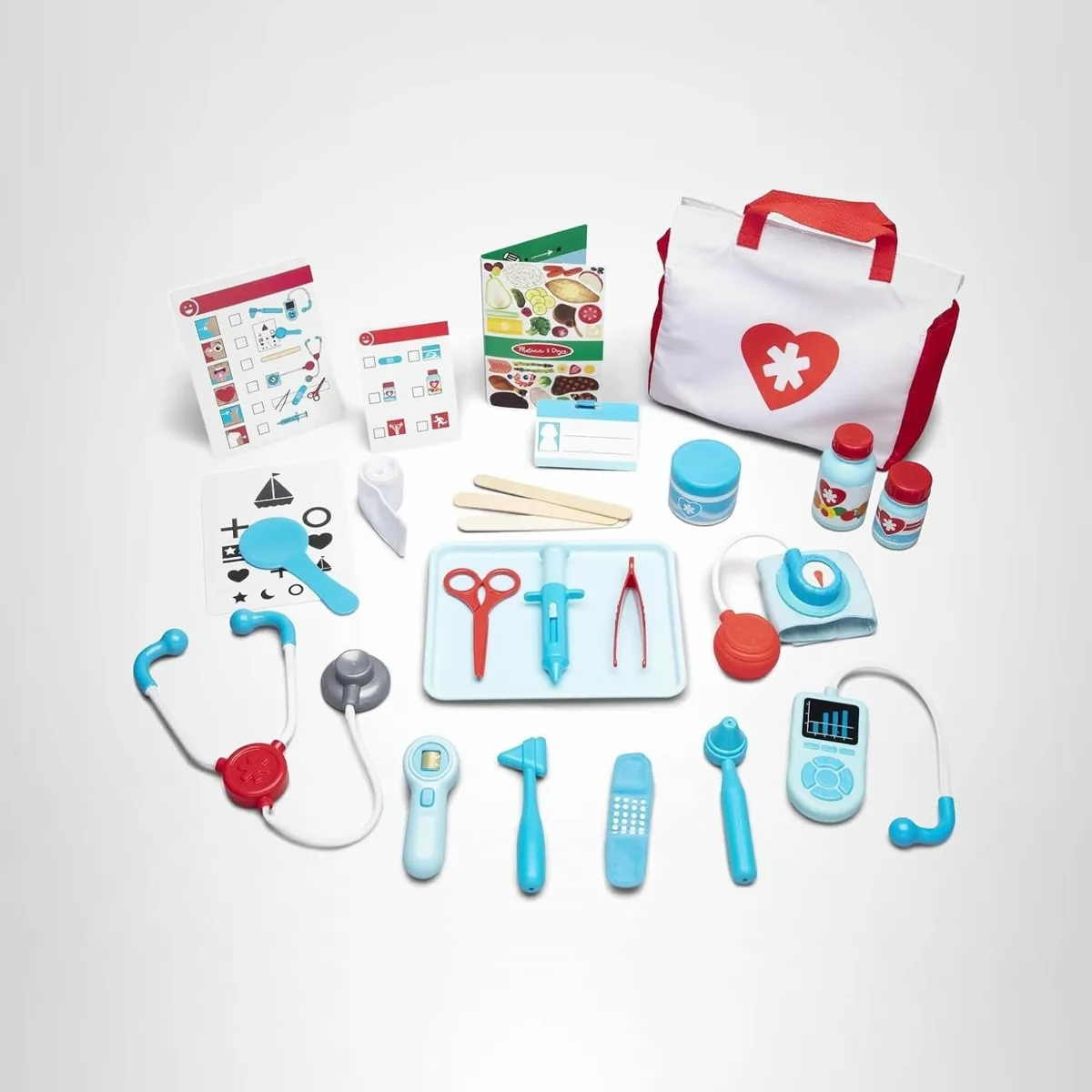 Toy doctor kit laid out with a stethoscope, thermometer, syringe, blood pressure cuff, tray and carry bag