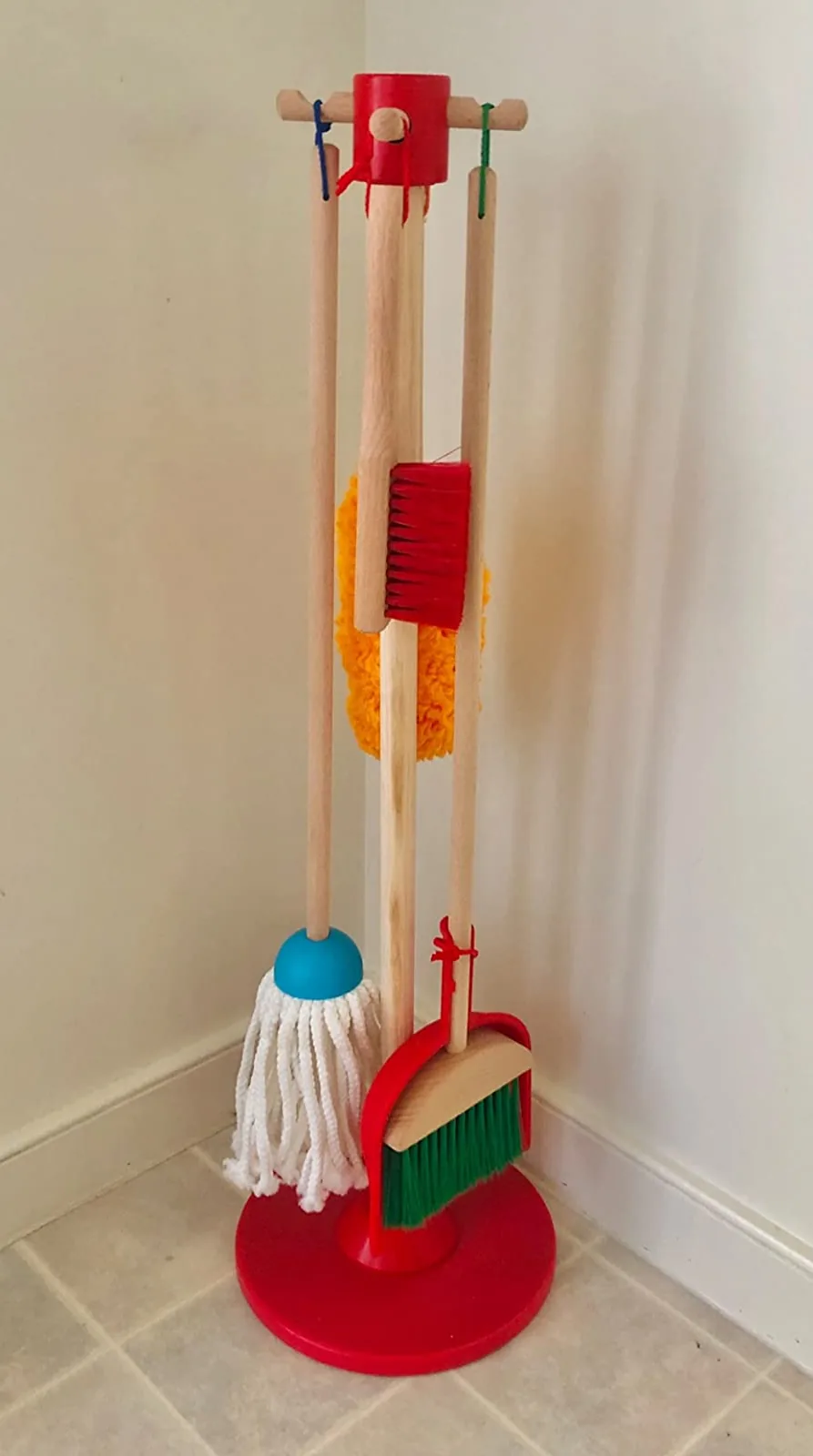 Child-sized broom, mop, duster, brush and dustpan hanging on a wooden stand