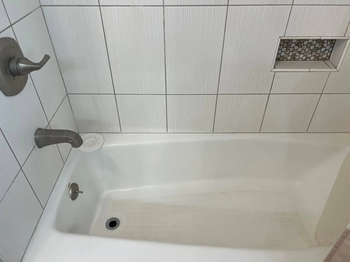 Bright white bathtub and tiled shower wall after a no-scrub shower spray