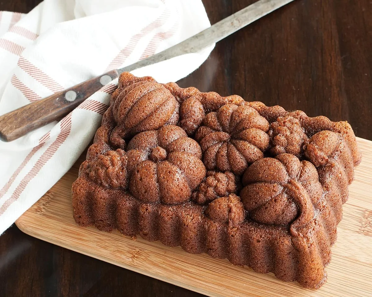 Loaf cake with an embossed pumpkin and gourd pattern on a wooden cutting board