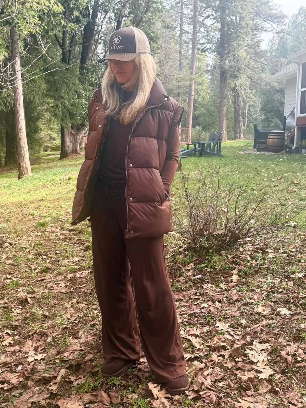 Oversized brown puffer vest layered over a long-sleeve top and wide-leg pants outdoors