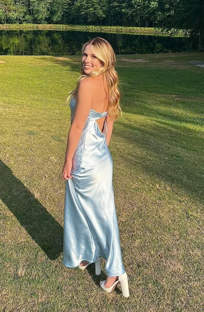Pale blue satin slip dress with an open back, worn on a lawn