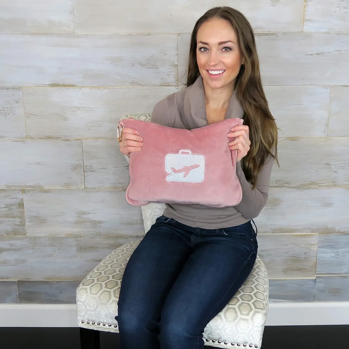 Pink plush travel blanket folded into its zip pouch pillow with a clip