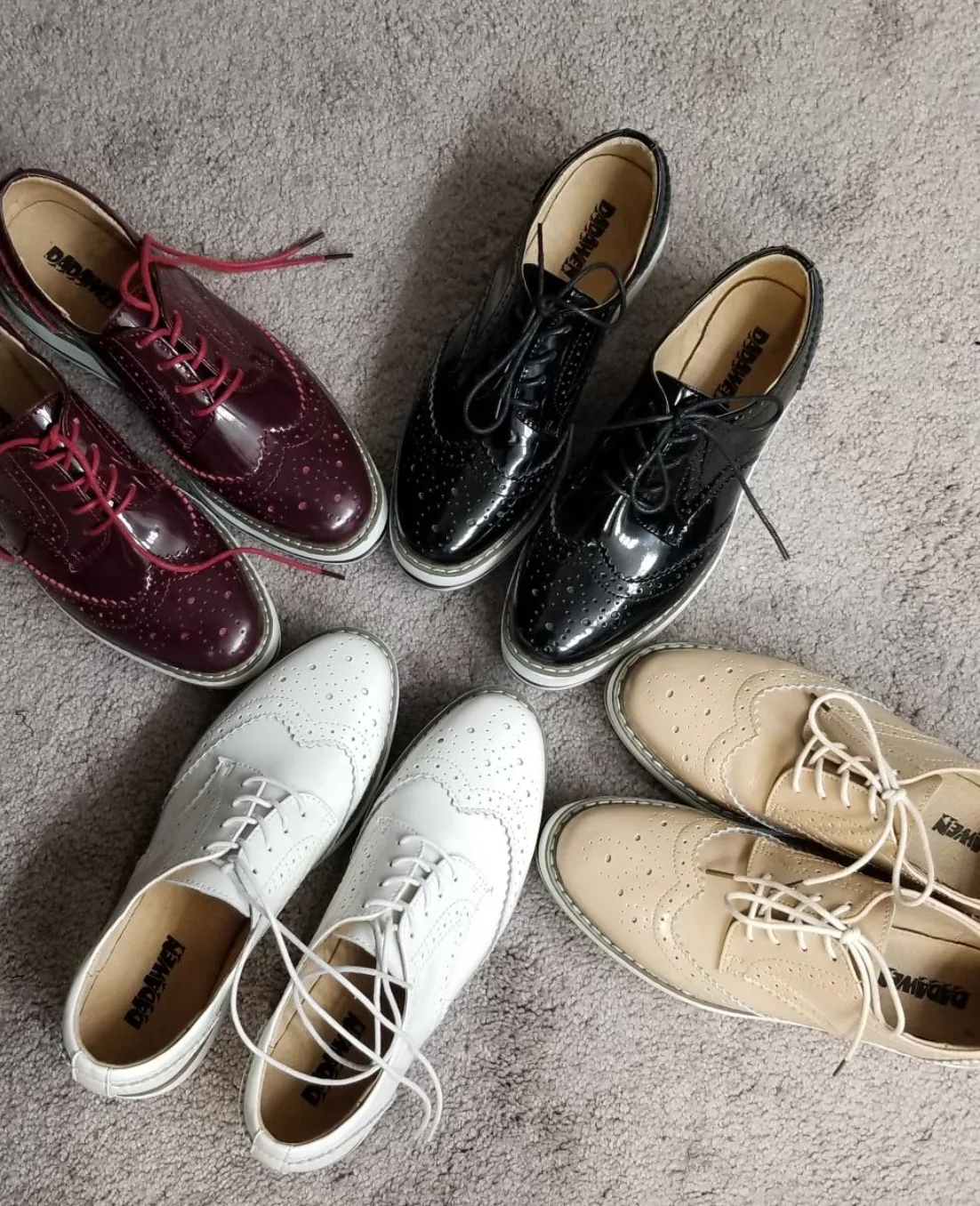 Platform wingtip oxfords in burgundy, black, white and beige arranged in a circle