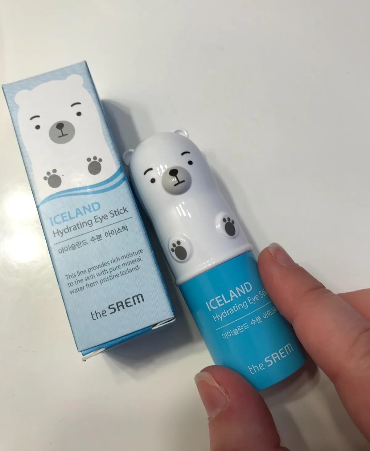 Hand holding a polar bear hydrating eye stick next to its box