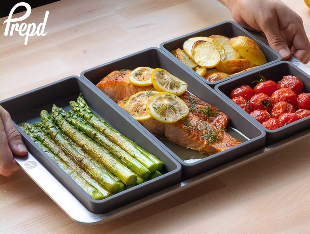 Sheet pan dividers holding asparagus, salmon, tomatoes and potatoes