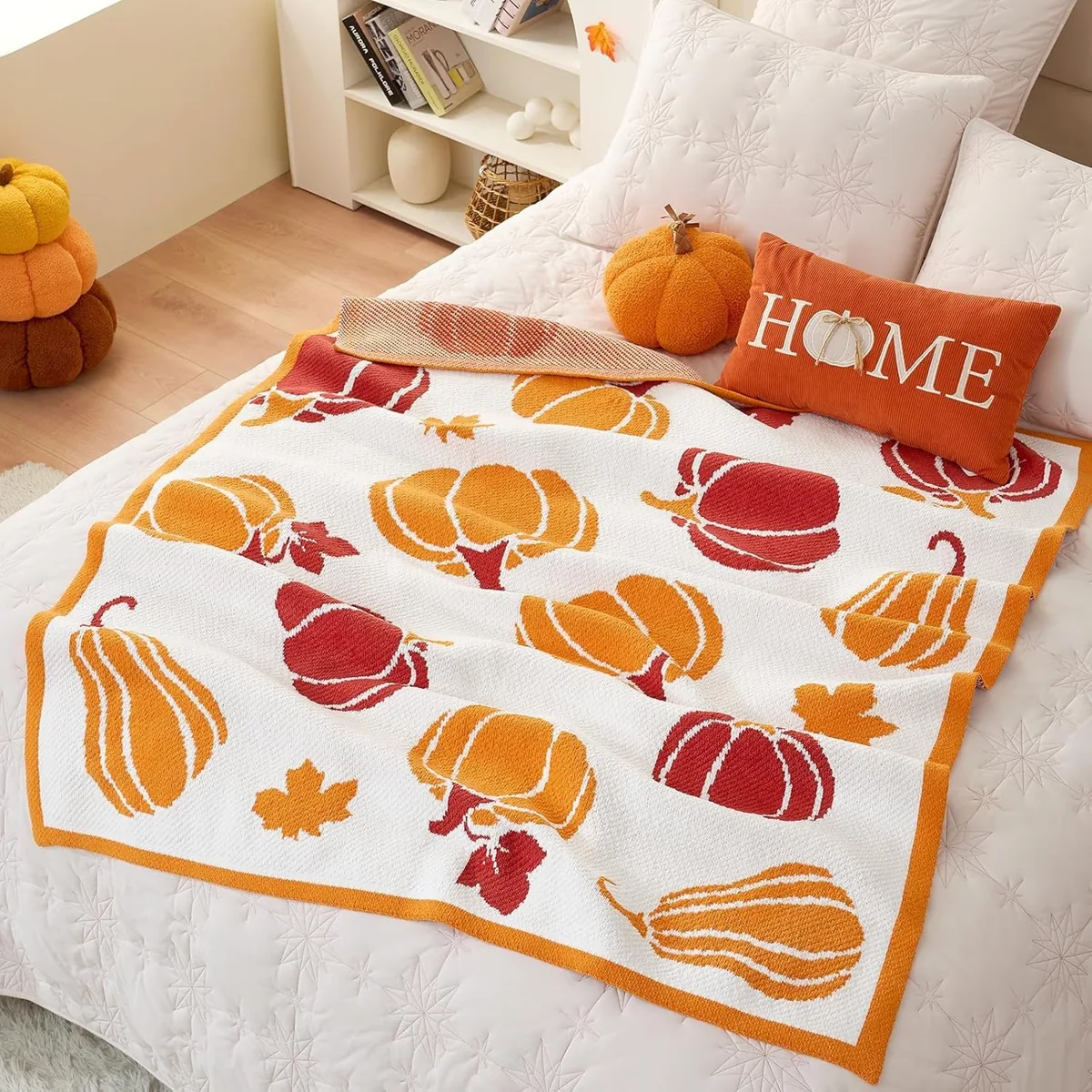 Cream chenille throw blanket with orange and red pumpkins spread over a bed