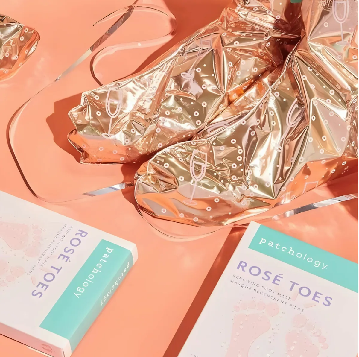 Shiny foil Patchology Rose Toes foot masks beside their packaging
