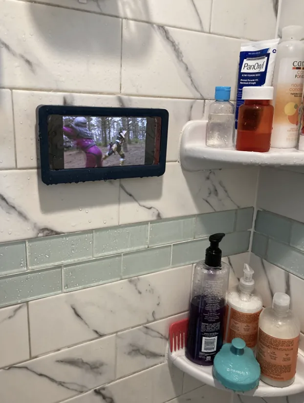 Phone holder on a shower wall playing a show