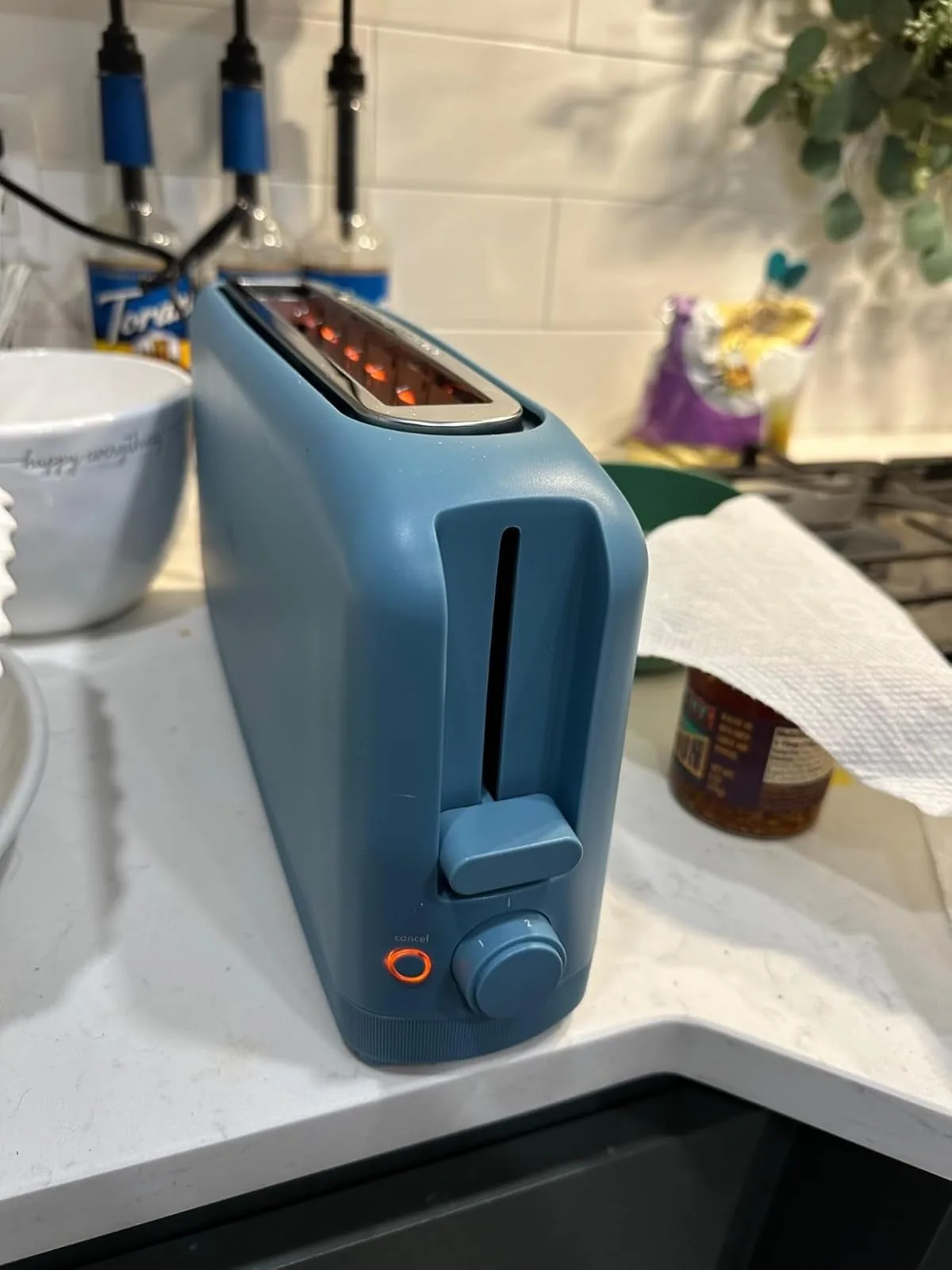 Slim blue toaster with a long slot on a kitchen counter