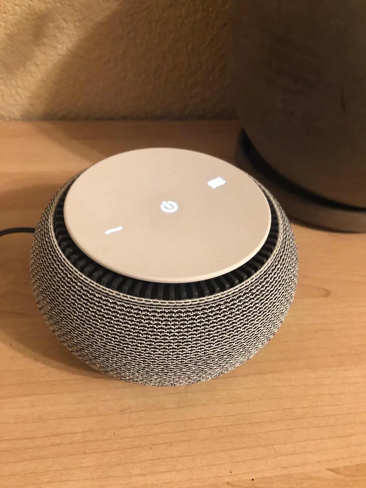 Snooz fan-based white noise machine with a fabric base on a wooden surface